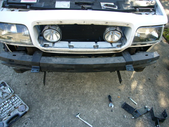 White 2000 Ford Crown Victoria front bumper with two auxiliary lights and tools scattered around