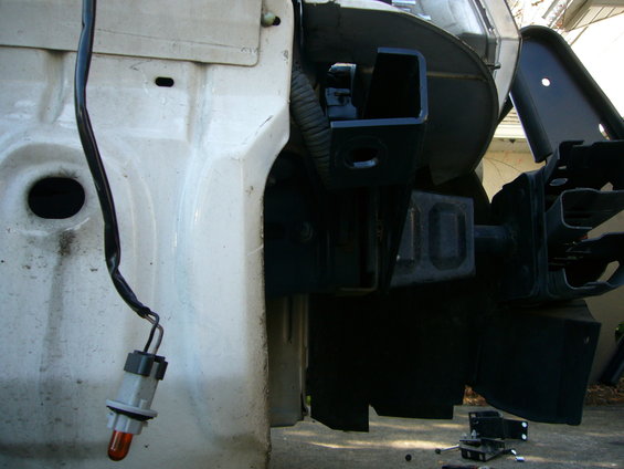 Close-up of a vehicle's frame with a black bumper bracket attached and a loose electrical connector