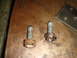 1996 Ford Bronco - Close-up view of two corroded bolts and a metal plate on a workbench.