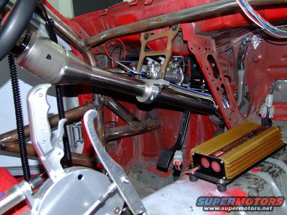 Custom race car interior showing roll cage, shifter, steering column, and an aftermarket electronic module