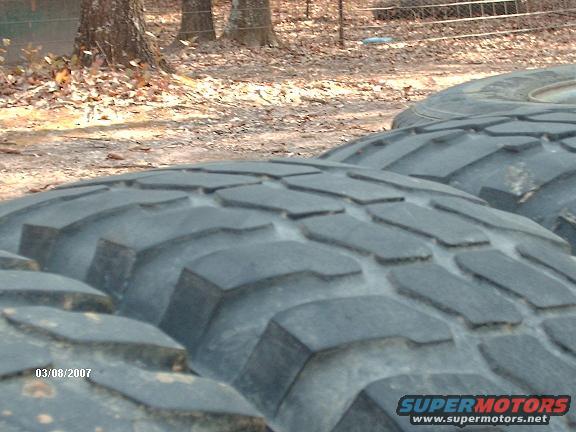 Close-up of large off-road tire tread with Supermotors.net logo