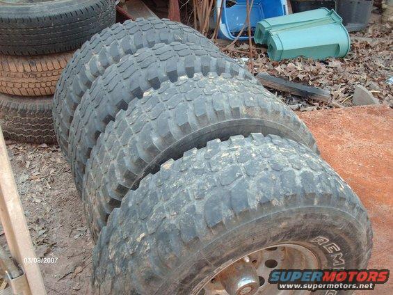 stack of four off-road tires, one with 'REM' visible on the sidewall