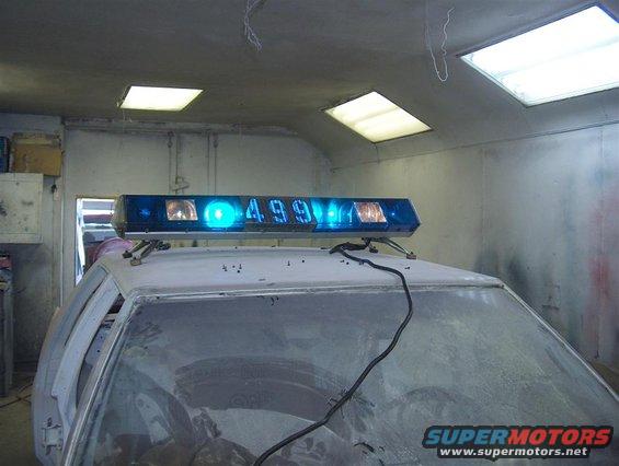 Police lightbar with digital display showing '499' mounted on the roof of a car