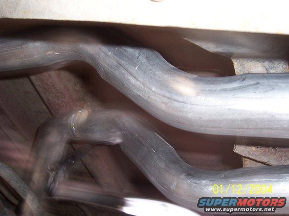 Underside view of dual exhaust pipes, one bent sharply