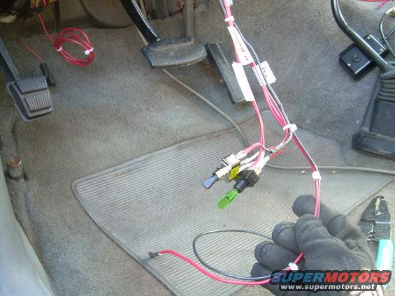 Close-up of vehicle interior showing aftermarket wiring, switches, and pedals