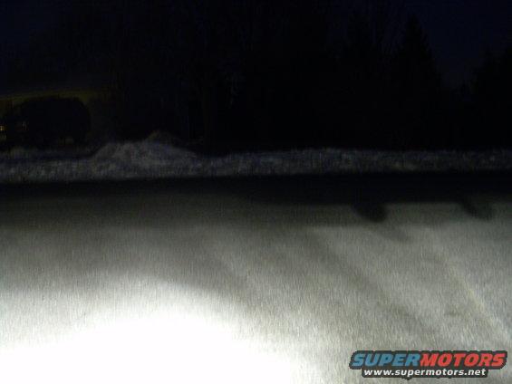 dark snowy scene with headlights on, supermotors.net logo in corner