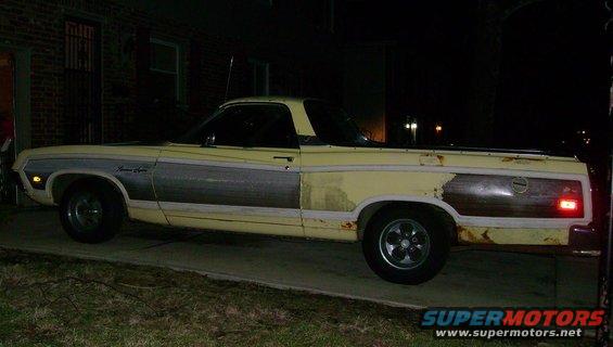 Yellow Ford Ranchero with wood paneling on the side, parked at night