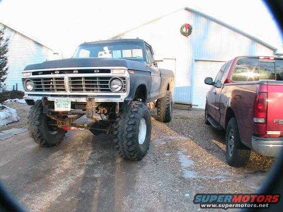 1977 Ford F-250 pickup truck with large tires parked next to a red pickup truck
