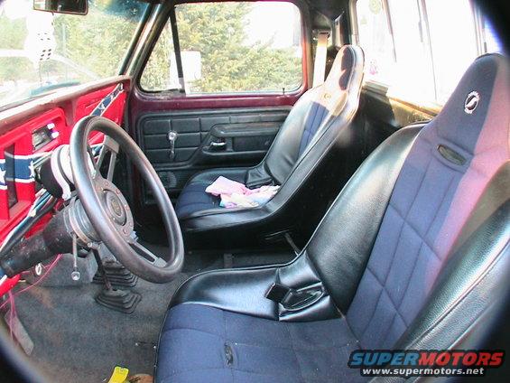 Truck interior with racing seats, aftermarket steering wheel, and a rebel flag decal on the dash