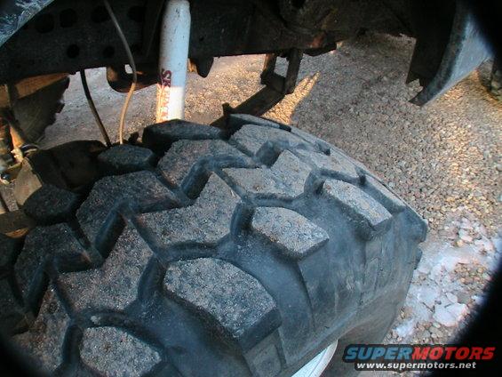 Close-up of a large, knobby off-road tire and suspension components of a truck