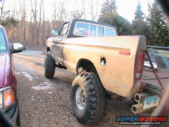 lifted pickup truck, rear 3/4 view, next to another vehicle