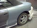 1994 Ford Probe - A car is undergoing bodywork, with primer applied to the rear fender and door.