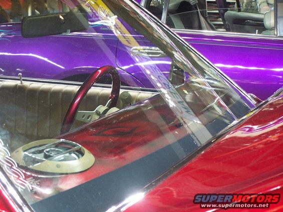 Red car interior with custom steering wheel and dashboard details, purple car visible behind