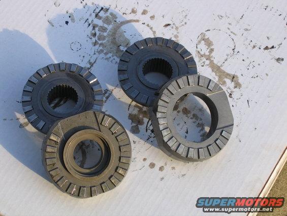 Four differential gears on a white surface with oil stains