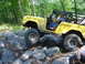 1975 Ford Bronco - A yellow 1975 Ford Bronco navigates a rocky obstacle course in a forest setting.