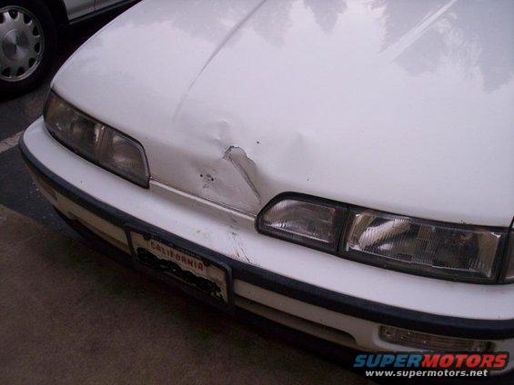 White car front with dented hood and California license plate