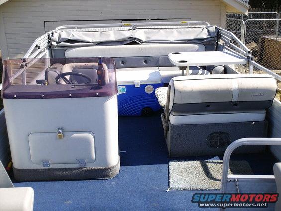 Boat interior with steering wheel, cooler, seats, and a table