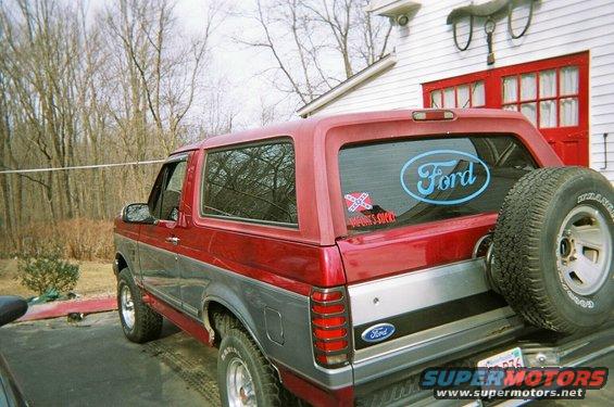 Red and gray 1994 Ford Bronco rear view with spare tire and Ford oval decal