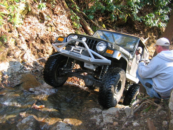 Black Jeep Wrangler TJ off-roading over rocks and water with BFGoodrich tires