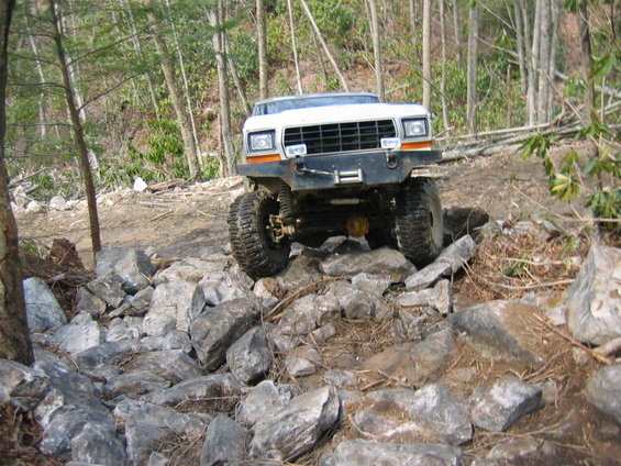 White 4x4 off-road vehicle navigating a rocky trail
