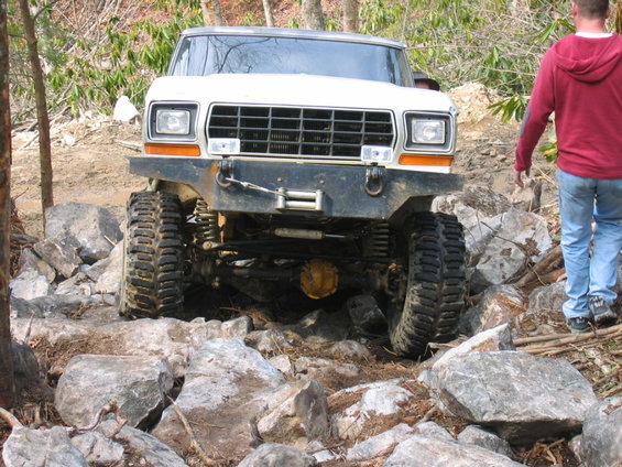 White off-road truck with large tires navigating rocky terrain