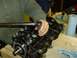 1982 Chevrolet C/K Pickup - A person uses a wrench to tighten bolts on a black engine component during a repair.
