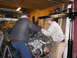 1978 Ford Bronco - Men are working on an engine swap in a garage, with a Bronco 4x4 Club banner in the background.