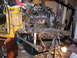 1978 Ford Bronco - Engine and chassis assembly undergoing work, with a mechanic positioned below for repairs or modifications.