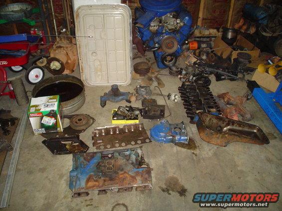 Engine block and various engine parts scattered on a concrete floor