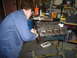 1976 Ford F-100 - Mechanic works on an engine block in a garage setting.