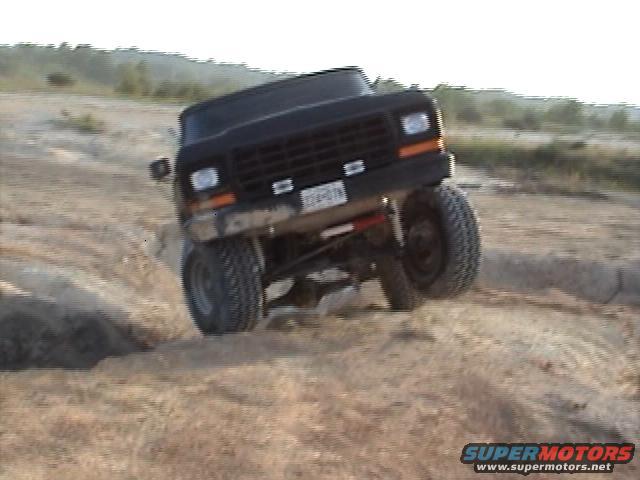 Black Ford Bronco going off-road, front wheel lifted