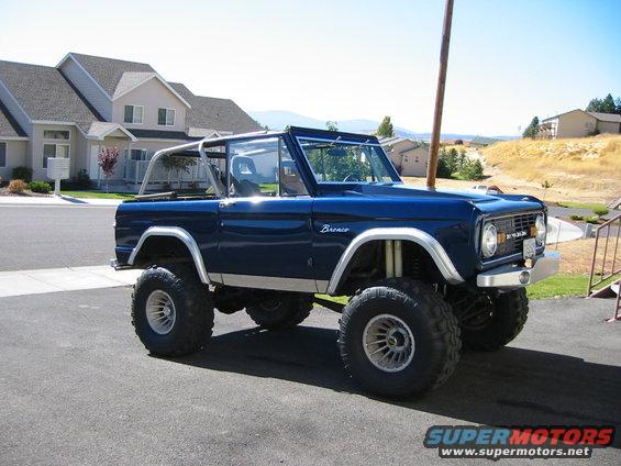 Blue Ford Bronco with lifted suspension and roll cage parked on asphalt