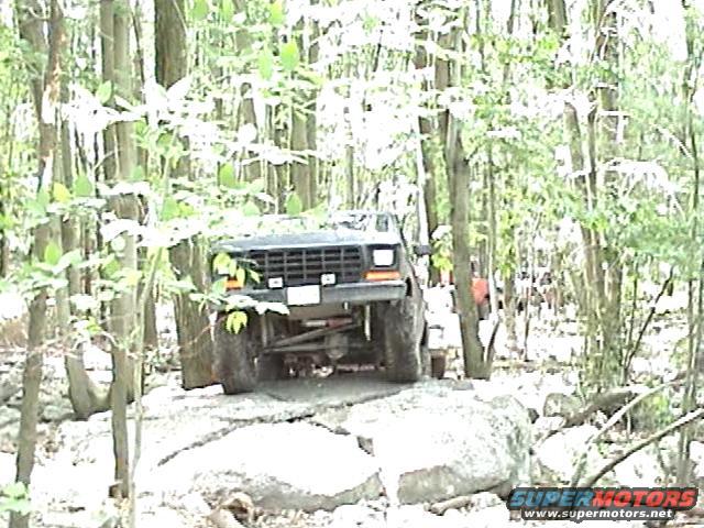 1978 Ford Bronco navigating rocky terrain in a wooded area