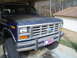 1984 Ford Bronco - Front view of a blue Ford Bronco, likely from the early 1980s, parked under a carport.