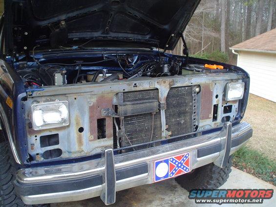 Blue Ford Bronco front view with hood open, showing engine and radiator. Chrome bumper has a Confederate flag sticker