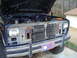 1984 Ford Bronco - Front view of a blue Ford Bronco with its hood open, revealing the engine compartment and radiator.