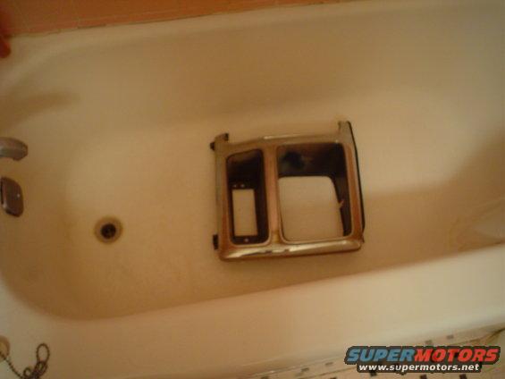 Chrome headlight bezel with dual openings, sitting in a bathtub