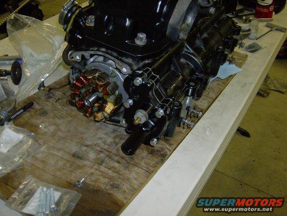 Black engine part with copper wiring on wooden surface