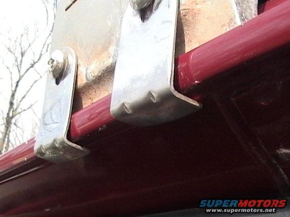 Red vehicle with two metal brackets attached to its side, showing screws and bent metal