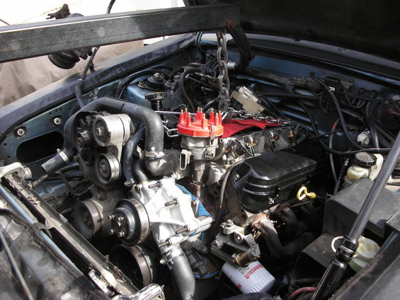 Engine bay with engine hoist, showing a V8 engine with red distributor cap