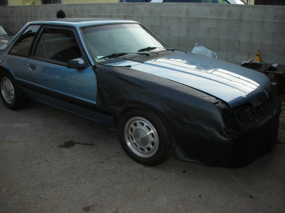 1990 Ford Mustang coupe, blue with black cover over front fender and bumper