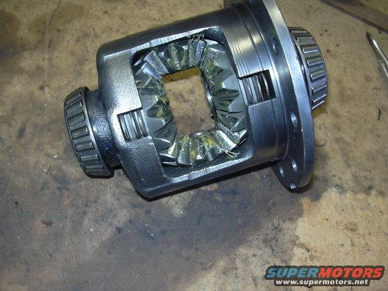 Close-up of a differential carrier with internal gears and bearings, resting on a workbench