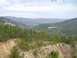 1999 Honda RANCHER - A scenic view of a forested mountain range with a visible dirt road and a watermark.