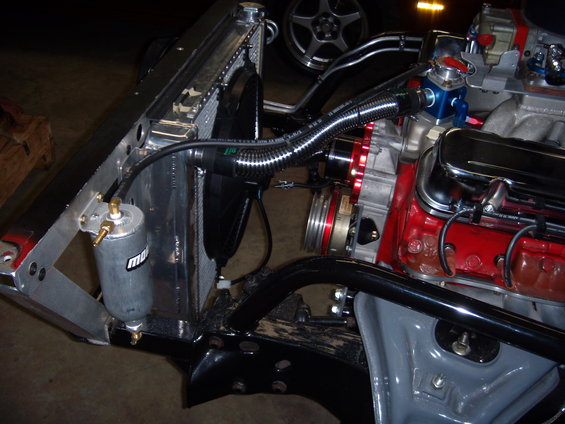 Engine bay with radiator, fan, and V8 engine parts. Has a Moroso catch can
