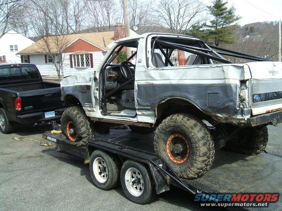 White and grey 1995 Ford Bronco with roll cage, on a trailer, 3q-front view