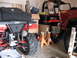 1979 Ford Bronco - An ATV and a red SUV are parked in a cluttered garage, surrounded by storage and equipment.