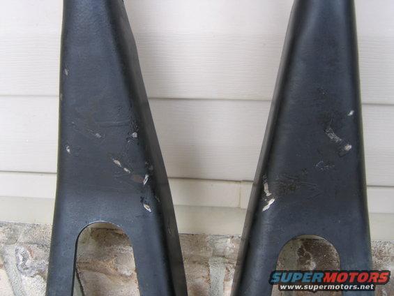 Two black metal suspension control arms with visible wear marks
