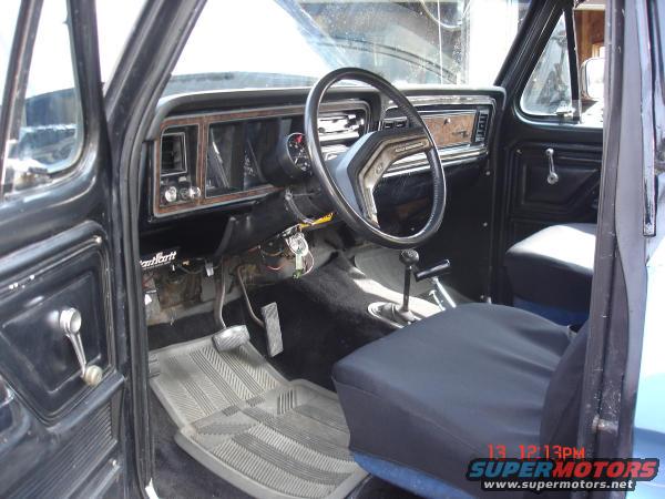 Interior shot of a 1979 Ford Bronco, showing the dashboard, steering wheel, seats, and door panel