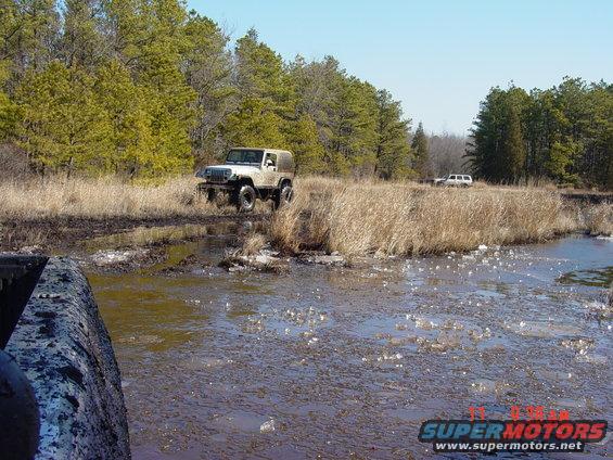 Jeep Wrangler driving through mud with another SUV in background