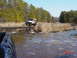 1995 Dodge 1500 - Two off-road vehicles navigate a muddy terrain with trees and dry grass.